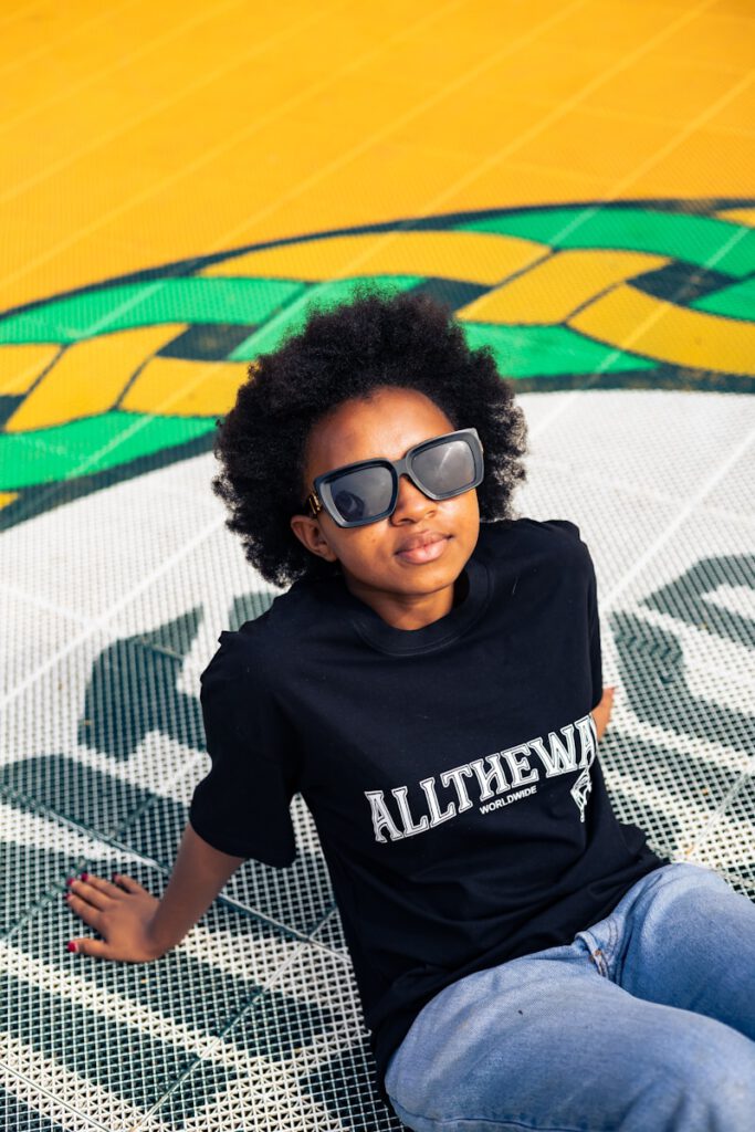 A young boy sitting on the ground wearing sunglasses